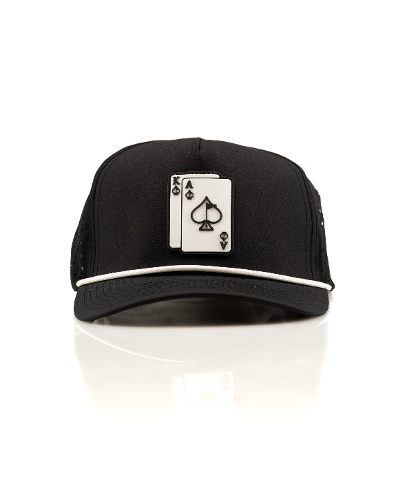 Ace/King Black perforated rope golf hat by Pins & Aces featuring a black poker-inspired design, braided rope accent, adjustable snapback, and built-in magnetic ball marker holder.