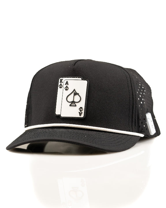 Ace/King Black perforated rope golf hat by Pins & Aces featuring a black poker-inspired design, braided rope accent, adjustable snapback, and built-in magnetic ball marker holder.
