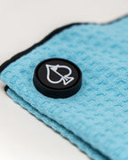 Sky blue Pins & Aces magnetic golf towel featuring waffle-knit fabric, a strong built-in magnet, center slit, and carabiner for attaching to a golf bag.