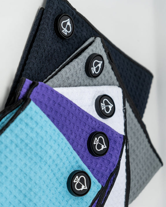 Sky blue Pins & Aces magnetic golf towel featuring waffle-knit fabric, a strong built-in magnet, center slit, and carabiner for attaching to a golf bag.