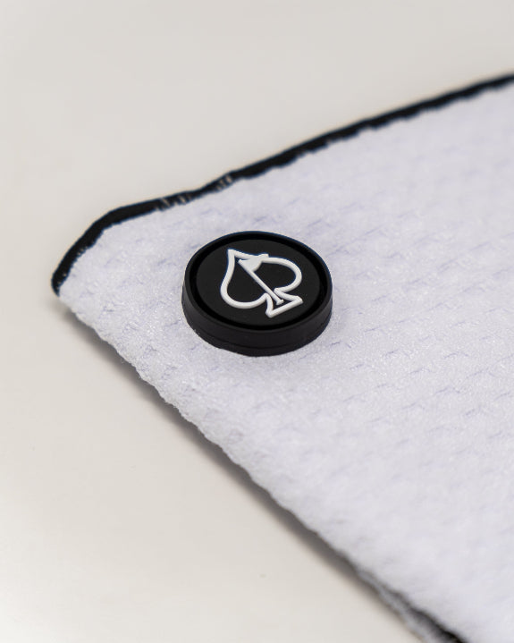 White Pins & Aces magnetic golf towel featuring durable waffle-knit fabric, a strong built-in magnet, center slit, and carabiner for attaching to a golf bag.