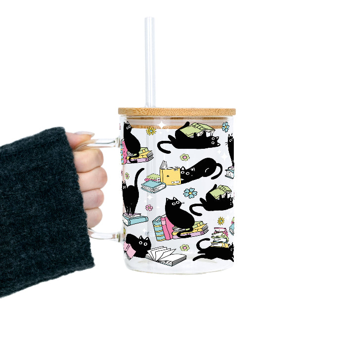 Black Cats on Books drinkware design featuring whimsical black cats lounging on colorful stacks of books with pastel flowers and bookish details.