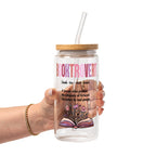 Clear glass cup with bamboo lid and straw featuring pink Booktrovert lettering, a definition about preferring fictional characters to real people, and an open book filled with pink and purple flowers.