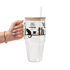 Bookish drinkware featuring a cozy wraparound bookshelf design with books, a curious kitty, and trailing green plants, available in glass cups, tumblers, and ceramic mugs.