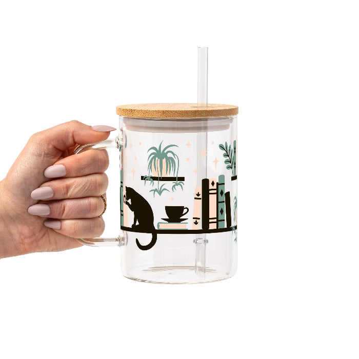 Bookish drinkware featuring a cozy wraparound bookshelf design with books, a curious kitty, and trailing green plants, available in glass cups, tumblers, and ceramic mugs.