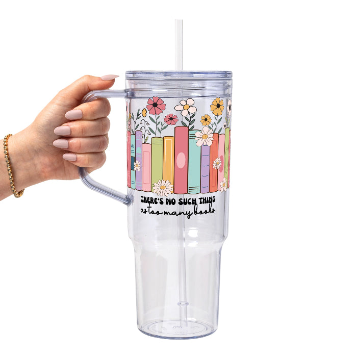 Clear glass cup with bamboo lid and straw featuring colorful pastel books surrounded by pink, yellow and white wildflowers with “There’s No Such Thing as Too Many Books” lettering.