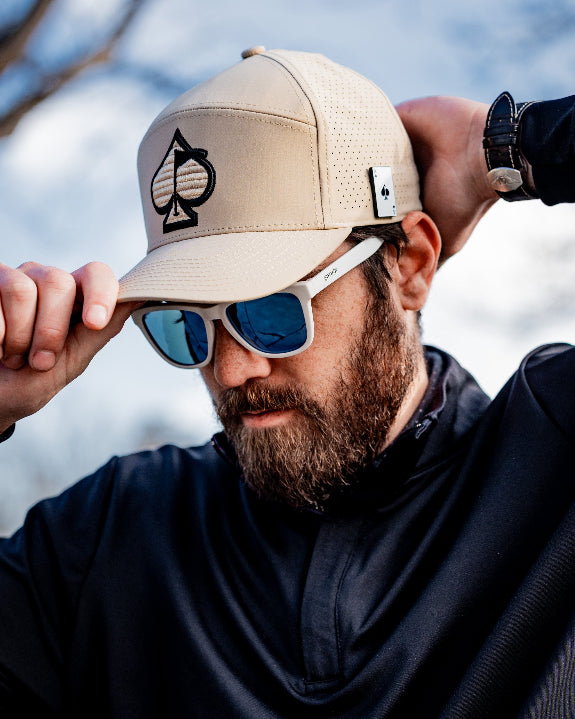 Tradesman Sand golf hat by Pins & Aces featuring a warm neutral sand colorway, adjustable snapback closure, and built-in magnetic golf ball marker holder.