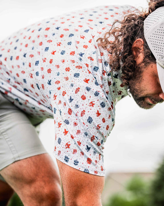Pins & Aces American Traditional men’s golf polo featuring a bold patriotic Americana and classic tattoo flash-inspired design with an athletic performance fit.