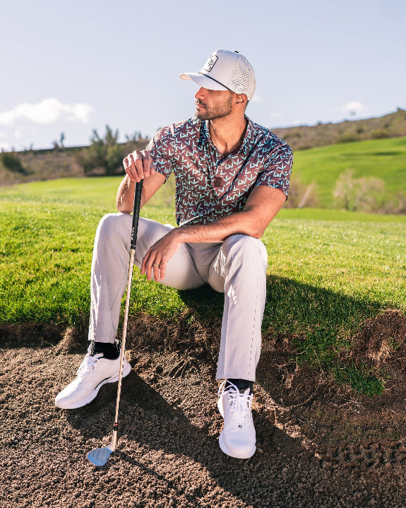 Men’s Cocoa Verde golf polo by Pins & Aces featuring a cocoa brown background with an all-over teal geometric print, short sleeves, and athletic performance fit.