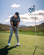 Men’s Man’s Best Friend Dark golf polo by Pins & Aces featuring a subtle dog-inspired pattern on a dark charcoal performance polo with short sleeves and athletic fit.