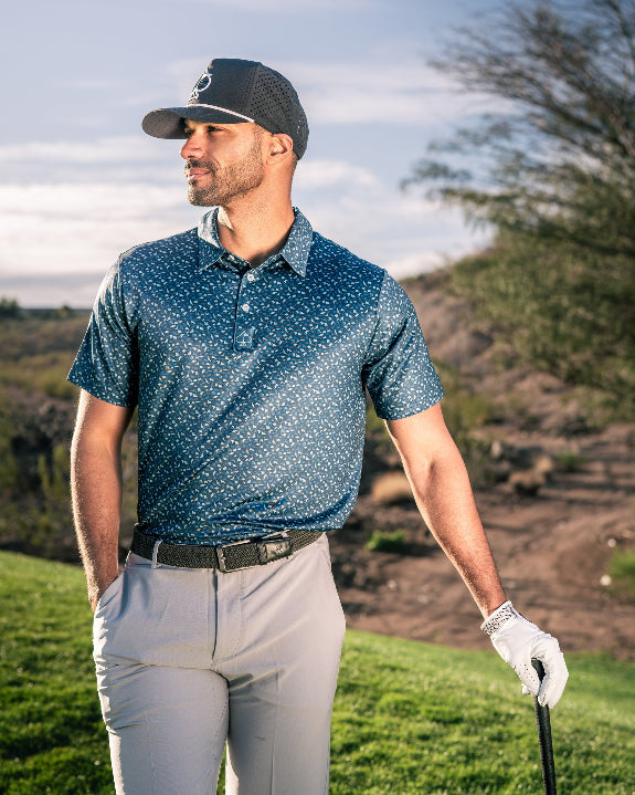 Men’s Manta Ray golf polo by Pins & Aces featuring a deep ocean blue all-over aquatic-inspired pattern, short sleeves, collared neckline, and athletic performance fit.