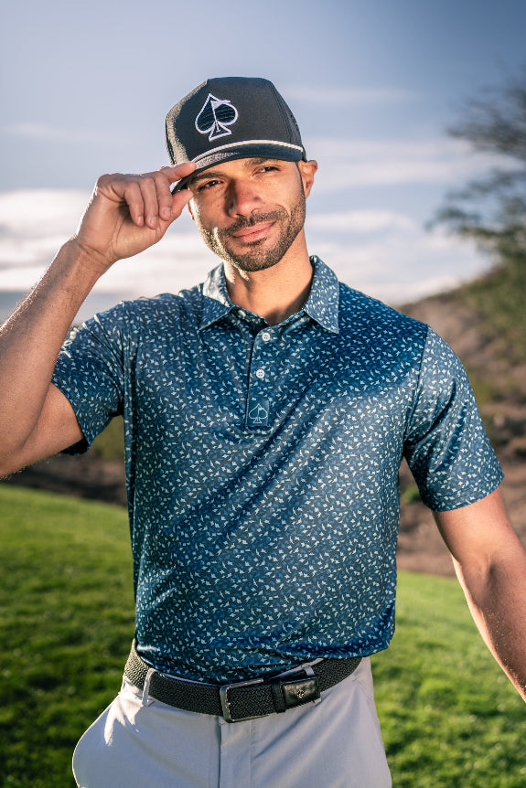 Men’s Manta Ray golf polo by Pins & Aces featuring a deep ocean blue all-over aquatic-inspired pattern, short sleeves, collared neckline, and athletic performance fit.
