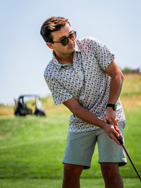 Men’s Retro Form golf polo by Pins & Aces featuring a vintage-inspired geometric print in neutral tones with burgundy accents, short sleeves, and an athletic fit.