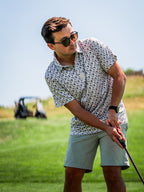 Men’s Retro Form golf polo by Pins & Aces featuring a vintage-inspired geometric print in neutral tones with burgundy accents, short sleeves, and an athletic fit.