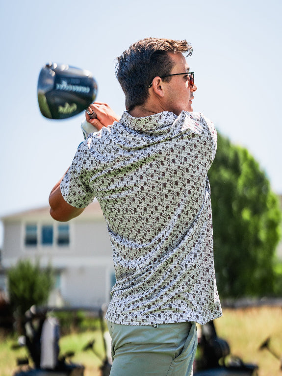 Men’s Retro Form golf polo by Pins & Aces featuring a vintage-inspired geometric print in neutral tones with burgundy accents, short sleeves, and an athletic fit.