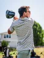 Men’s Retro Form golf polo by Pins & Aces featuring a vintage-inspired geometric print in neutral tones with burgundy accents, short sleeves, and an athletic fit.