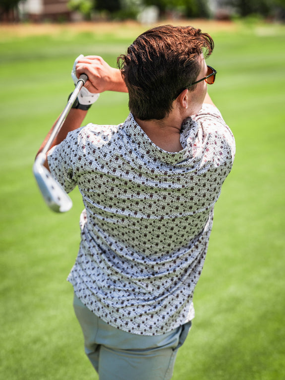 Men’s Retro Form golf polo by Pins & Aces featuring a vintage-inspired geometric print in neutral tones with burgundy accents, short sleeves, and an athletic fit.
