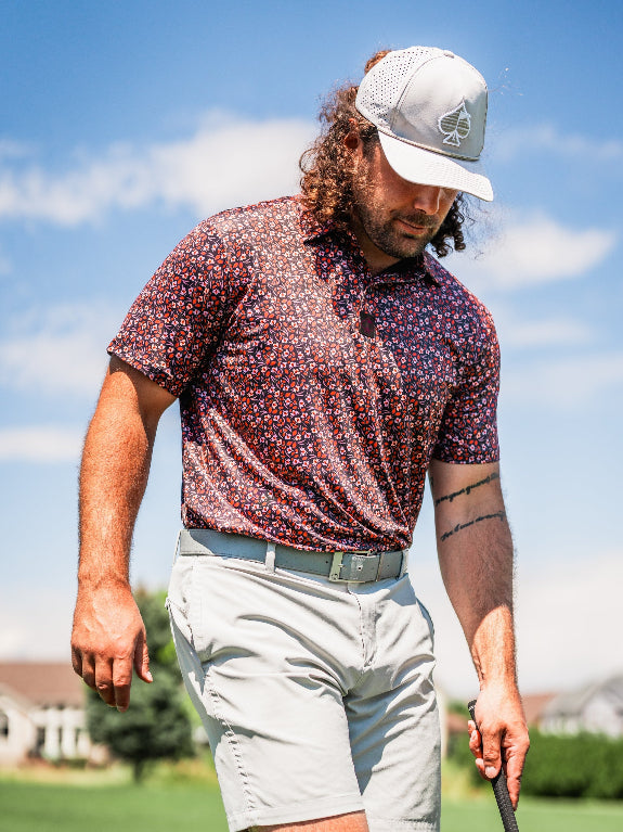 Men’s Shadow Rose golf polo by Pins & Aces featuring an all-over red and muted rose floral print on a black background with short sleeves and an athletic performance fit.