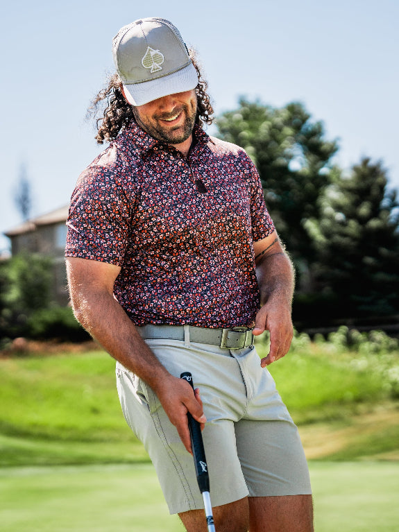 Men’s Shadow Rose golf polo by Pins & Aces featuring an all-over red and muted rose floral print on a black background with short sleeves and an athletic performance fit.