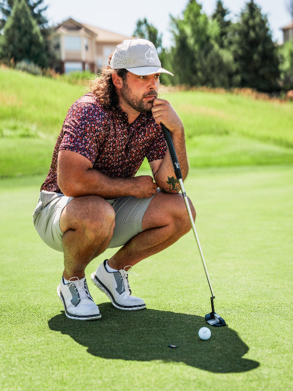 Men’s Shadow Rose golf polo by Pins & Aces featuring an all-over red and muted rose floral print on a black background with short sleeves and an athletic performance fit.