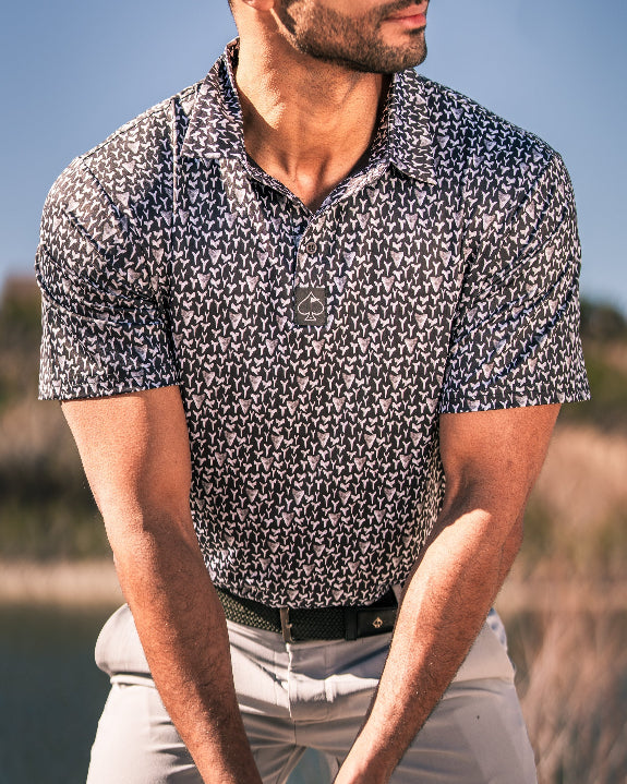 Men’s Shark Tooth golf polo by Pins & Aces featuring an all-over black, charcoal, gray, and white shark tooth-inspired micro print with short sleeves and an athletic performance fit.