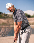 Men’s Shark Tooth golf polo by Pins & Aces featuring an all-over black, charcoal, gray, and white shark tooth-inspired micro print with short sleeves and an athletic performance fit.