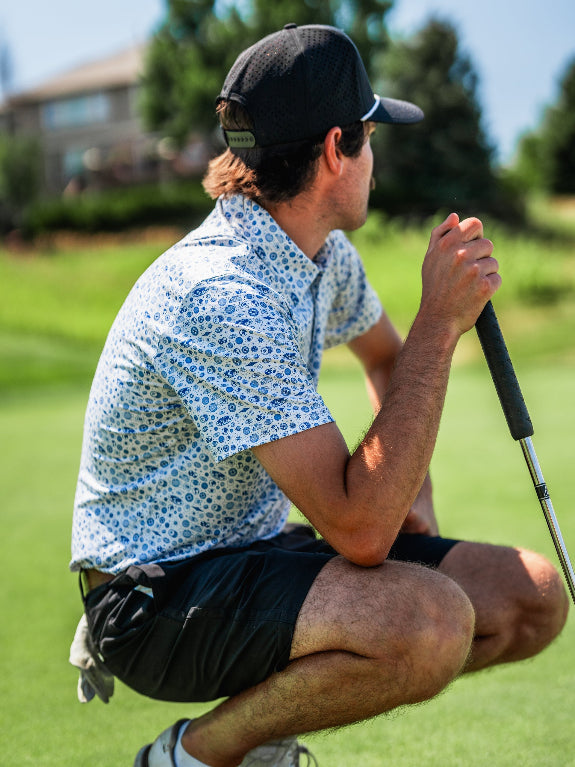 Pins & Aces Signal Boost men’s performance golf polo featuring an athletic fit with breathable fast-wicking fabric, SPF 45+ protection, and built-in sunglasses holder.