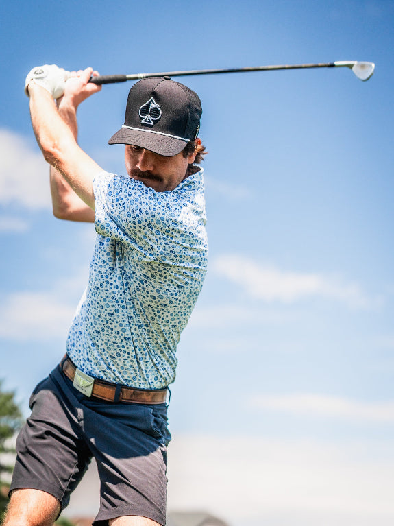 Pins & Aces Signal Boost men’s performance golf polo featuring an athletic fit with breathable fast-wicking fabric, SPF 45+ protection, and built-in sunglasses holder.