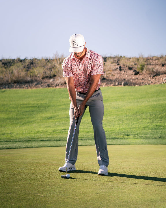 Men’s Soft Spoken golf polo by Pins & Aces featuring a subtle coral, red, navy, and white micro floral print with short sleeves and an athletic performance fit.