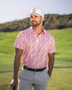 Men’s Soft Spoken golf polo by Pins & Aces featuring a subtle coral, red, navy, and white micro floral print with short sleeves and an athletic performance fit.