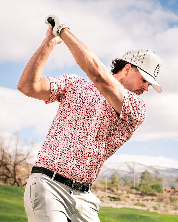 Men’s Soft Spoken golf polo by Pins & Aces featuring a subtle coral, red, navy, and white micro floral print with short sleeves and an athletic performance fit.