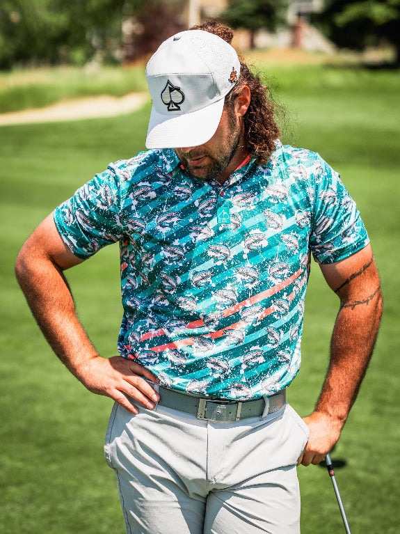 Men’s Trout Splatter golf polo by Pins & Aces featuring an all-over trout fishing print with teal, aqua, coral, and white splatter details and an athletic performance fit.
