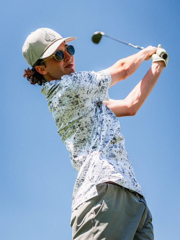 Men’s White Noise golf polo by Pins & Aces featuring a subtle white and gray abstract pattern, short sleeves, and an athletic performance fit.