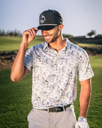 Men’s White Noise golf polo by Pins & Aces featuring a subtle white and gray abstract pattern, short sleeves, and an athletic performance fit.