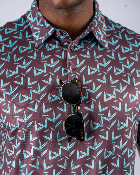 Men’s Cocoa Verde golf polo by Pins & Aces featuring a cocoa brown background with an all-over teal geometric print, short sleeves, and athletic performance fit.