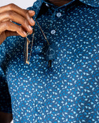 Men’s Manta Ray golf polo by Pins & Aces featuring a deep ocean blue all-over aquatic-inspired pattern, short sleeves, collared neckline, and athletic performance fit.