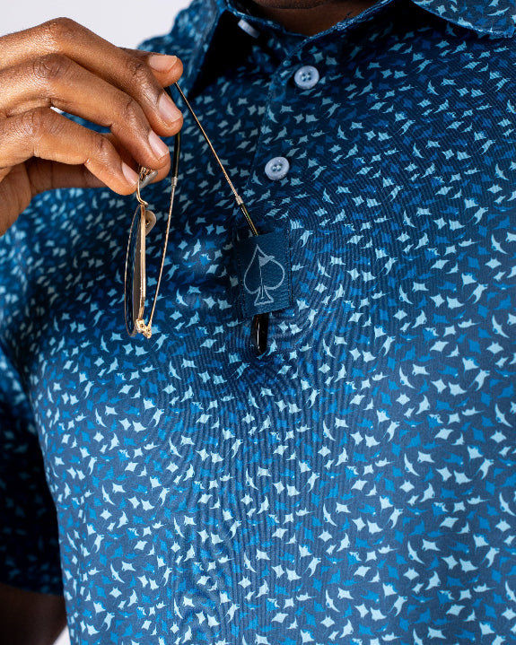 Men’s Manta Ray golf polo by Pins & Aces featuring a deep ocean blue all-over aquatic-inspired pattern, short sleeves, collared neckline, and athletic performance fit.