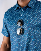 Men’s Manta Ray golf polo by Pins & Aces featuring a deep ocean blue all-over aquatic-inspired pattern, short sleeves, collared neckline, and athletic performance fit.