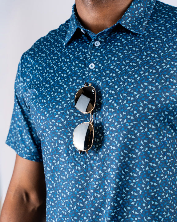 Men’s Manta Ray golf polo by Pins & Aces featuring a deep ocean blue all-over aquatic-inspired pattern, short sleeves, collared neckline, and athletic performance fit.