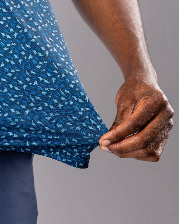 Men’s Manta Ray golf polo by Pins & Aces featuring a deep ocean blue all-over aquatic-inspired pattern, short sleeves, collared neckline, and athletic performance fit.