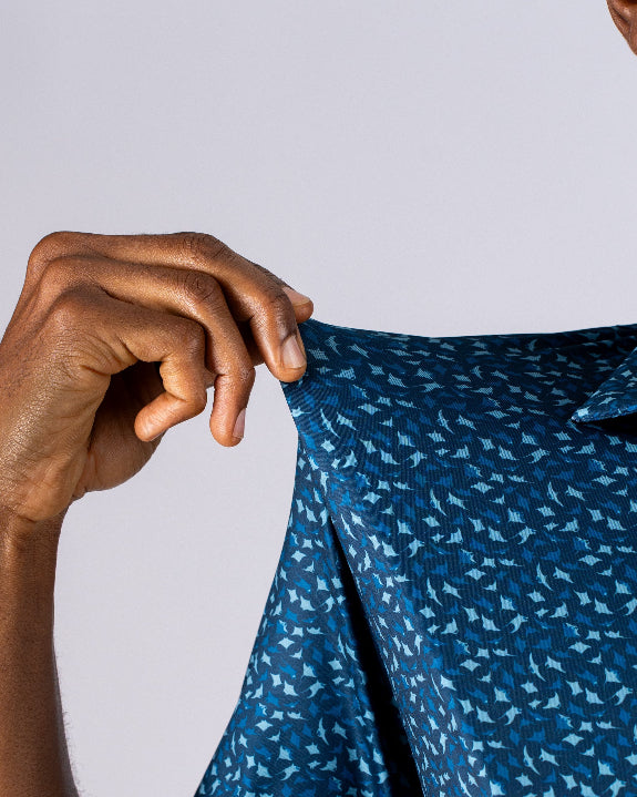 Men’s Manta Ray golf polo by Pins & Aces featuring a deep ocean blue all-over aquatic-inspired pattern, short sleeves, collared neckline, and athletic performance fit.