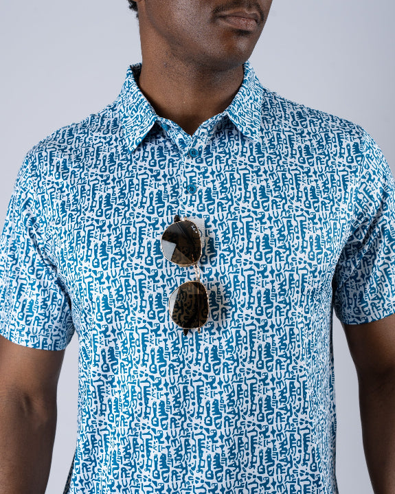 Men’s Maze Craze golf polo by Pins & Aces featuring an all-over blue maze-inspired geometric pattern with short sleeves and an athletic performance fit.