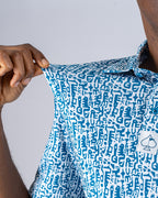 Men’s Maze Craze golf polo by Pins & Aces featuring an all-over blue maze-inspired geometric pattern with short sleeves and an athletic performance fit.