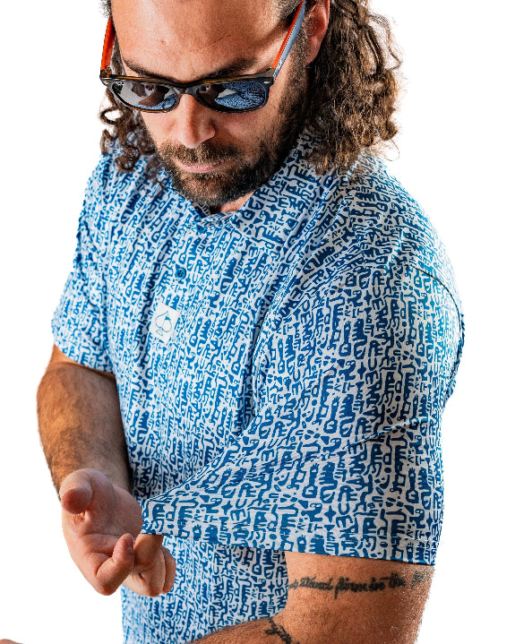 Men’s Maze Craze golf polo by Pins & Aces featuring an all-over blue maze-inspired geometric pattern with short sleeves and an athletic performance fit.