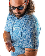 Men’s Maze Craze golf polo by Pins & Aces featuring an all-over blue maze-inspired geometric pattern with short sleeves and an athletic performance fit.