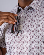 Men’s Retro Form golf polo by Pins & Aces featuring a vintage-inspired geometric print in neutral tones with burgundy accents, short sleeves, and an athletic fit.