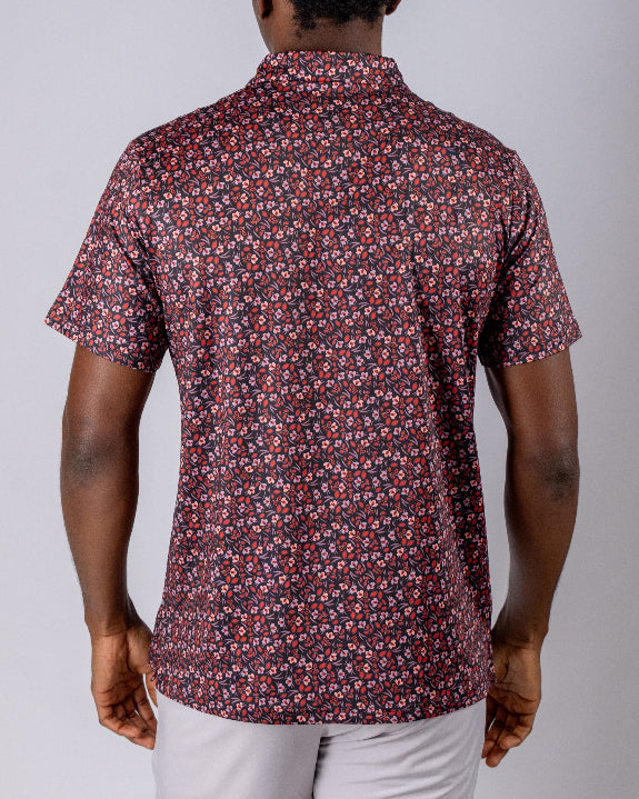 Men’s Shadow Rose golf polo by Pins & Aces featuring an all-over red and muted rose floral print on a black background with short sleeves and an athletic performance fit.