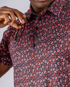 Men’s Shadow Rose golf polo by Pins & Aces featuring an all-over red and muted rose floral print on a black background with short sleeves and an athletic performance fit.