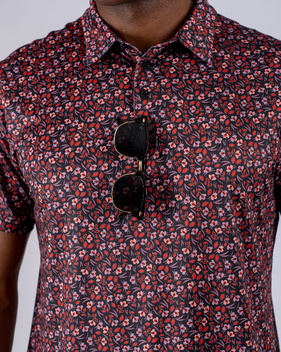 Men’s Shadow Rose golf polo by Pins & Aces featuring an all-over red and muted rose floral print on a black background with short sleeves and an athletic performance fit.