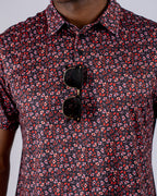 Men’s Shadow Rose golf polo by Pins & Aces featuring an all-over red and muted rose floral print on a black background with short sleeves and an athletic performance fit.